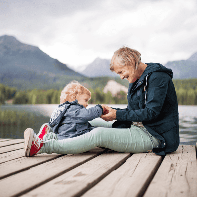 A retired woman playing with her granddaughter near a lake
